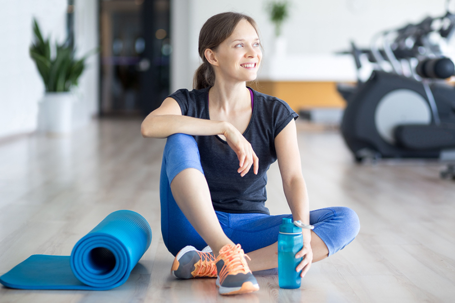 happy-sporty-woman-on-floor-with-mat-and-water-img